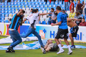 Torcedor caído no chão e sendo chutado por outro, durante briga no México, em estádio de futebol