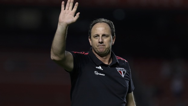 Rogério Ceni, acenando com o braço direito, vestindo camisa da comissão técnica do São Paulo, preta, com o escudo do time.