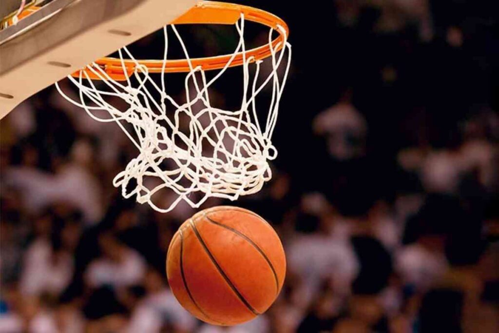 Cesta de basquete e bola passando pela cesta durante jogo.