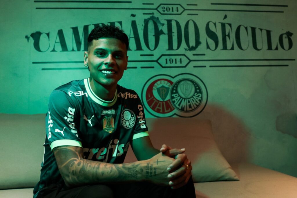 Palmeiras contrata volante colombiano ex-Flamengo e Guarani - Richard Ríos é apresentado pelo Palmeiras, sentado em sofá com iluminação verde e os dizeres ao fundo "Campeão do Século", relativo ao Verdão.