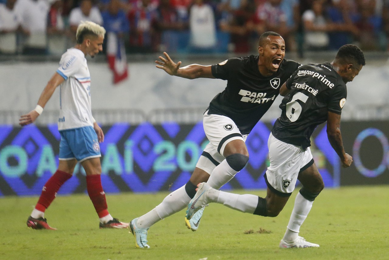Botafogo vence o Bahia fora de casa e segue 100% no Brasileirão - Marlon Freitas corre para abraçar Tchê Tchê, autor do gol do Botafogo, enquanto que um jogador do Bahia, cabisbaixo, lamenta o gol sofrido