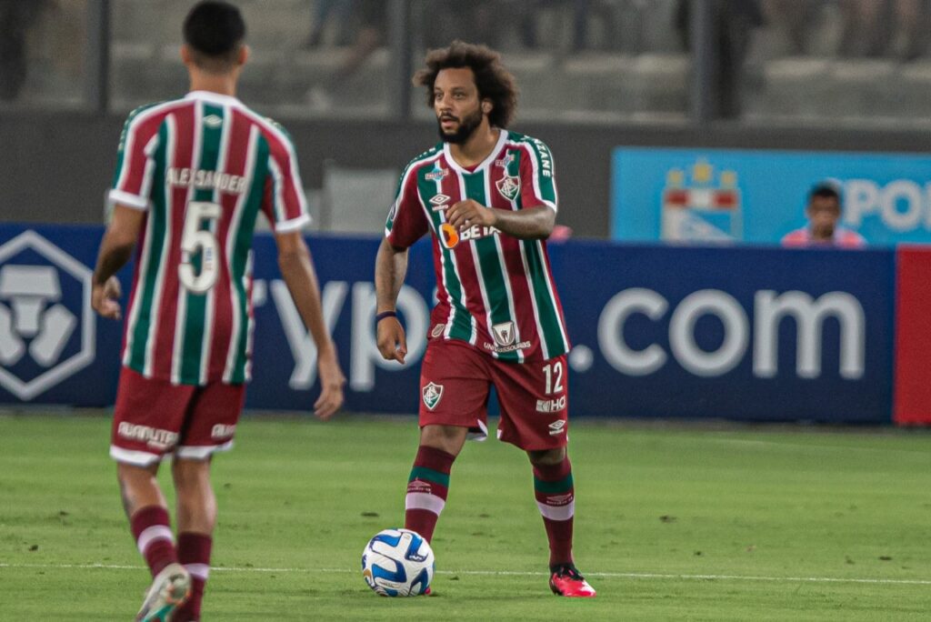 Marcelo vira dúvida no Fluminense: Marcelo carrega a bola com o pé direito, enquanto Alexsander, de costas na imagem, o observa de frente