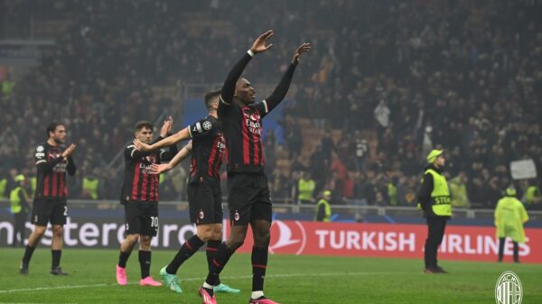 Milan vence Napoli. No primeiro plano da imagem, o jogador aparece comemorando o gol com os braços levantados. Ele veste uniforme preto com detalhes em vermelho e branco.
