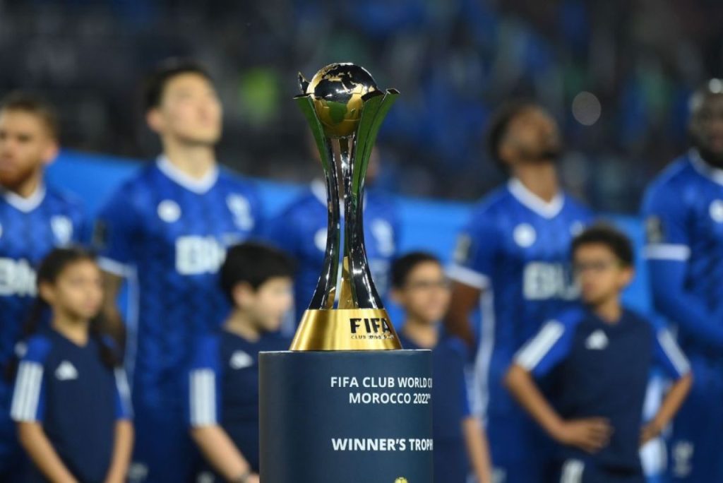 Taça do Mundial de Clubes de 2022, com elenco do Al-Hilal ao fundo