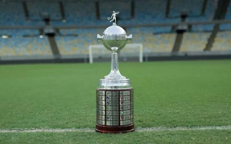 troféu da libertadores à mostra em um campo de futebol