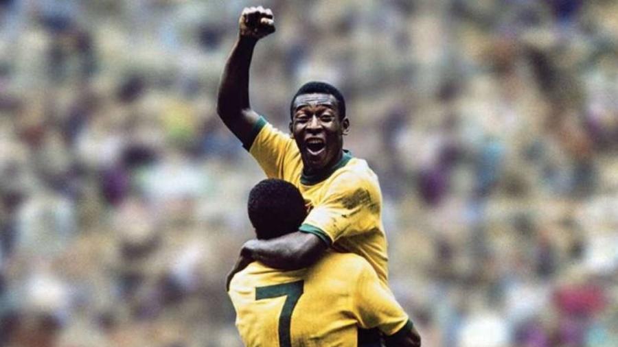 cena histórica de pelé comemorando gol, com o braço erguido no ar e sendo levantado por Jairzinho