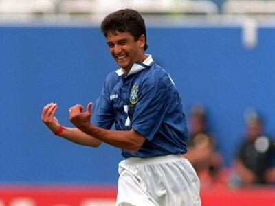 Bebeto, jogador da Seleção Brasileira, vestindo camisa azul e short branco do uniforme do Brasil, comemorando gol imitando o embalar de um bebê.