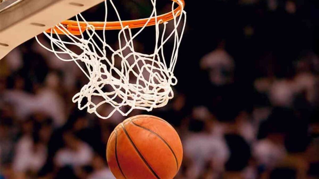 Cesta de basquete e bola passando pela cesta durante jogo.