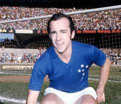 Tostão vestindo uniforme azul do Cruzeiro e short banco, agachado no gramado, em estádio lotado.