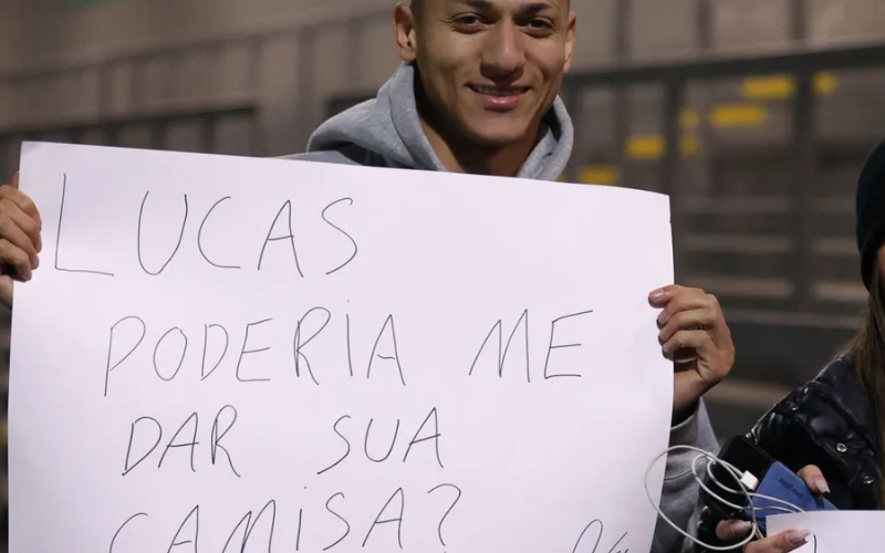 Richarlison na arquibancada com cartaz.