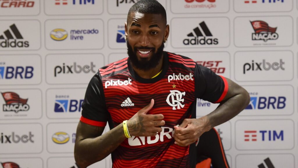 Gerson é apresentado no Flamengo. Na foto, o meio-campista aparece vestindo a camisa do clube e apontando para o escudo
