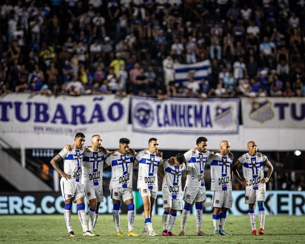 Os jogadores do Água Santa aparecem um ao lado do outro e olham para a meta do gol aguardando a cobrança de pênaltis.