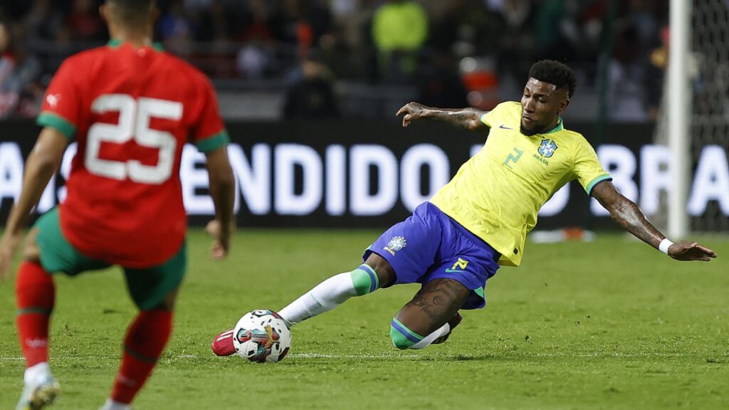Em jogo do Brasil, Emerson Royal tem lesão no joelho e passará por cirurgia - Lateral do Brasil, Emerson Royal dá carrinho na bola enquanto jogador do Marrocos o observa