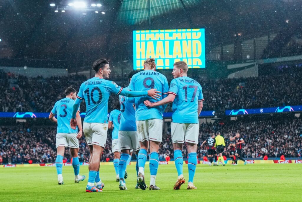 Haaland faz 5 gols, City goleia Leipzig e vai às quartas da Champions - Haaland comemora seu gol com Grealish e De Bruyne, enquanto seu nome é exibido no telão do estádio