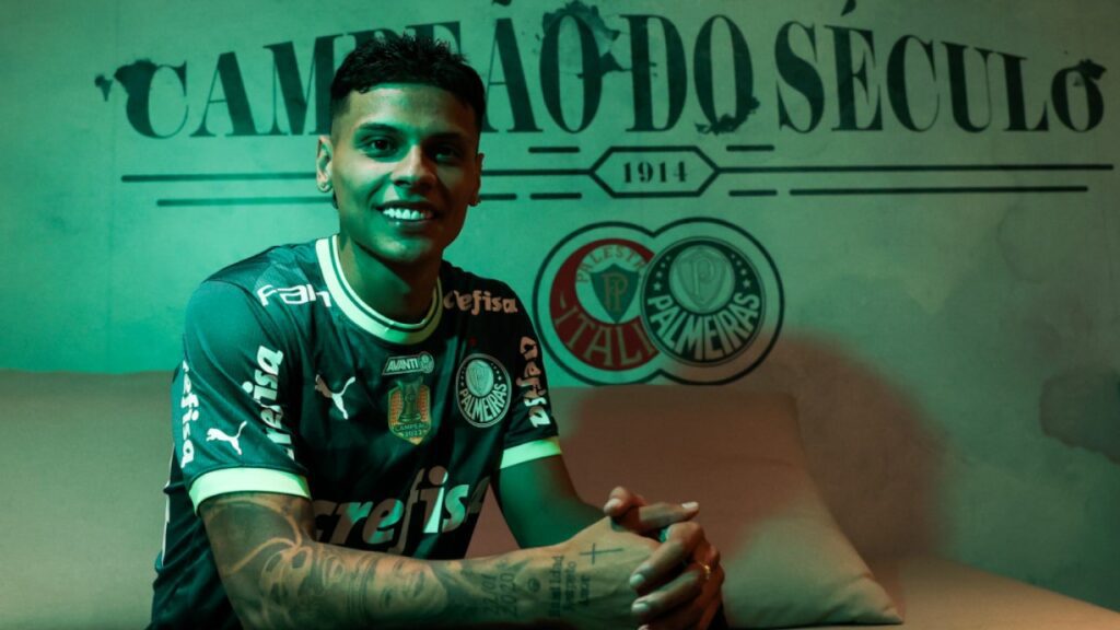 Palmeiras contrata volante colombiano ex-Flamengo e Guarani - Richard Ríos é apresentado pelo Palmeiras, sentado em sofá com iluminação verde e os dizeres ao fundo "Campeão do Século", relativo ao Verdão.