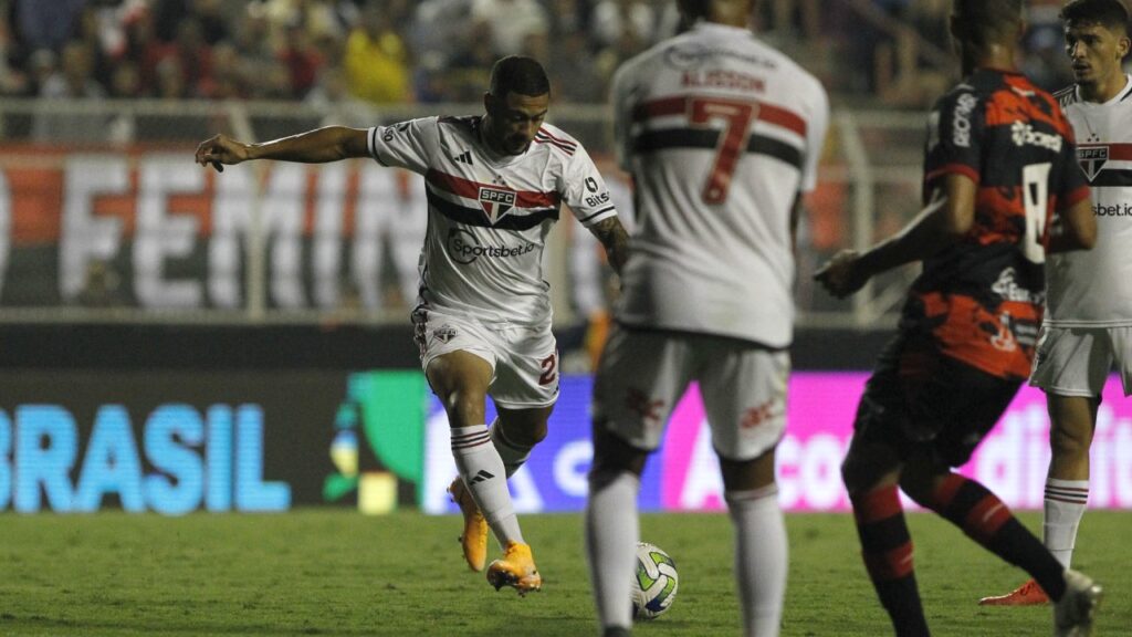 Com gol de Wellington Rato, São Paulo vence o Ituano e avança na Copa do Brasil - Wellington Rato, do São Paulo, arrisca chute que terminaria em gol no duelo contra o Ituano. Na imagem, o meia Alisson aparece de costas, em primeiro plano, dentro da grande área, pedindo a bola, enquanto o marcador do Ituano se aproxima dele.