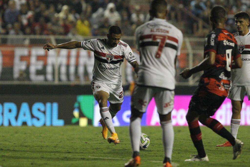 Com gol de Wellington Rato, São Paulo vence o Ituano e avança na Copa do Brasil - Wellington Rato, do São Paulo, arrisca chute que terminaria em gol no duelo contra o Ituano. Na imagem, o meia Alisson aparece de costas, em primeiro plano, dentro da grande área, pedindo a bola, enquanto o marcador do Ituano se aproxima dele.