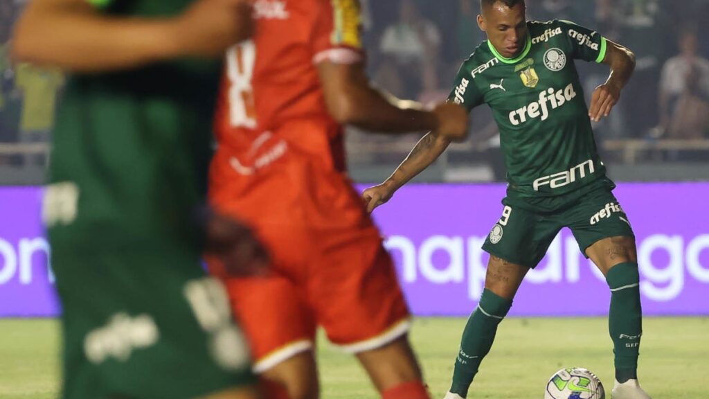 Palmeiras empata com o Tombense e vai às oitavas da Copa do Brasil - Ao fundo, no lado direito, Breno Lopes arma o chute que terminaria em gol do Palmeiras. Em primeiro plano, de costas, aparecem um jogador do Tombense e outro do Palmeiras, ambos desfocados