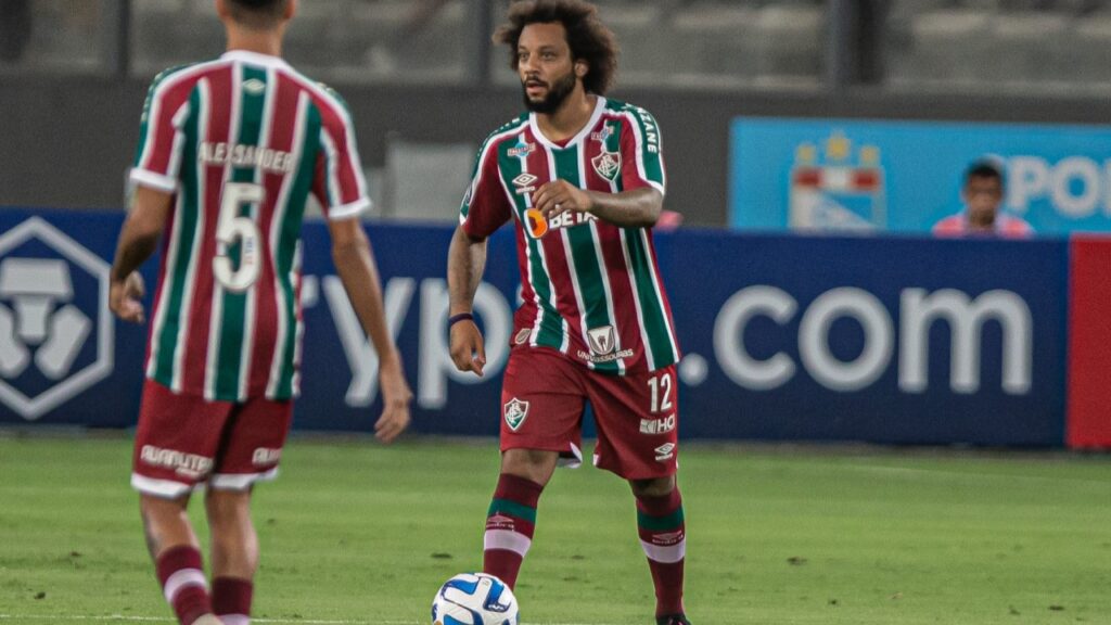 Marcelo vira dúvida no Fluminense: Marcelo carrega a bola com o pé direito, enquanto Alexsander, de costas na imagem, o observa de frente