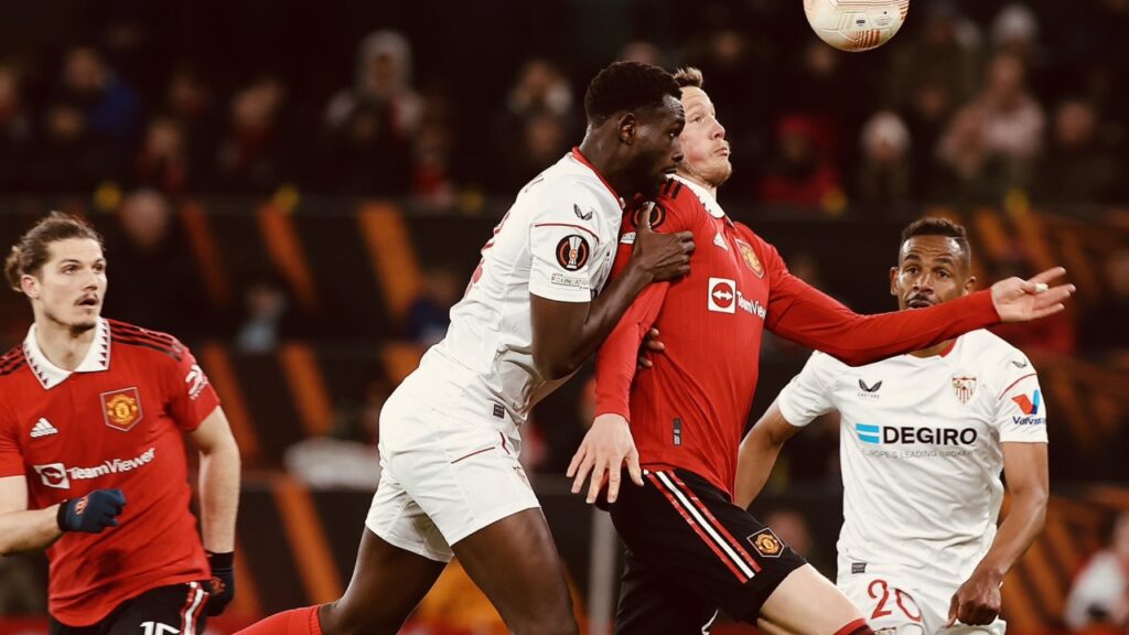 Com 2 gols contra no fim, Manchester United e Sevilla empatam pela Liga Europa - Jogadores de Sevilla e Manchester United disputam a bola pelo alto e se chocam