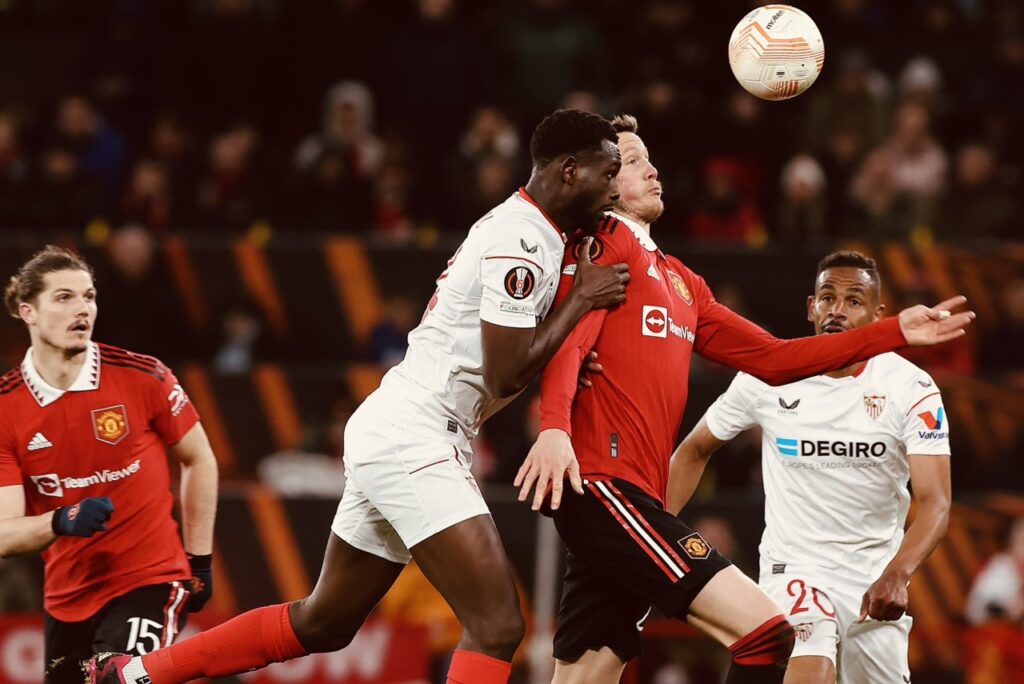 Com 2 gols contra no fim, Manchester United e Sevilla empatam pela Liga Europa - Jogadores de Sevilla e Manchester United disputam a bola pelo alto e se chocam