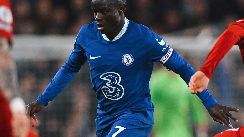 Chelsea empata com Liverpool. O jogador aparece em primeiro plano. Ele está correndo e usa um uniforme azul com detalhes em branco.