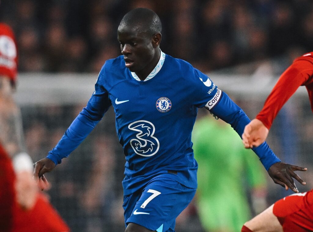 Chelsea empata com Liverpool. O jogador aparece em primeiro plano. Ele está correndo e usa um uniforme azul com detalhes em branco.