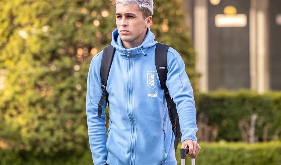 Botafogo contrata Diego Hernández, que deve chegar em julho. Foto: Divulgação/Uruguai. Jogador tem cabelos platinados, veste moletom azul, segura uma mala na mão e uma bolsa nas costas.