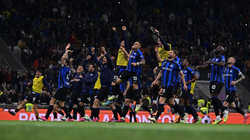 Inter de Milão vai à final da Copa Itália. Jogadores estão no centro de campo. Todos pulam e gritam comemorando a classificação da equipe. Eles vestem uniforme azul com listras verticais pretas e calção preto.