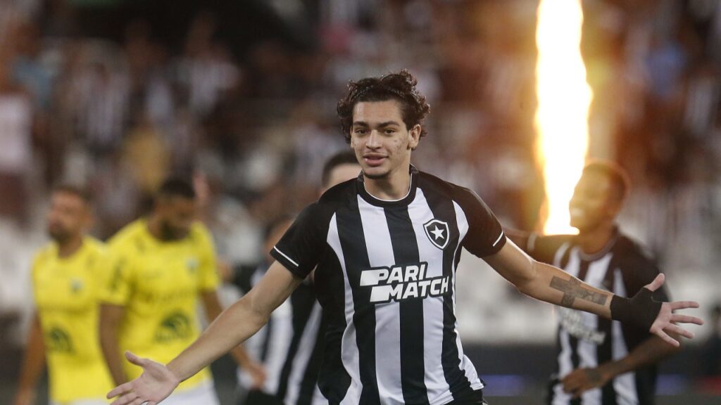 Botafogo bate o Ypiranga-RS e está nas oitavas de final da Copa do Brasil - Matheus Nascimento, do Botafogo, corre com os braços abertos em comemoração ao gol que acabou de marcar. Ao fundo, jogadores do Ypiranga-RS, um jogador do Botafogo e um lança chamas pirotécnico do clube, que sai fogo a cada gol