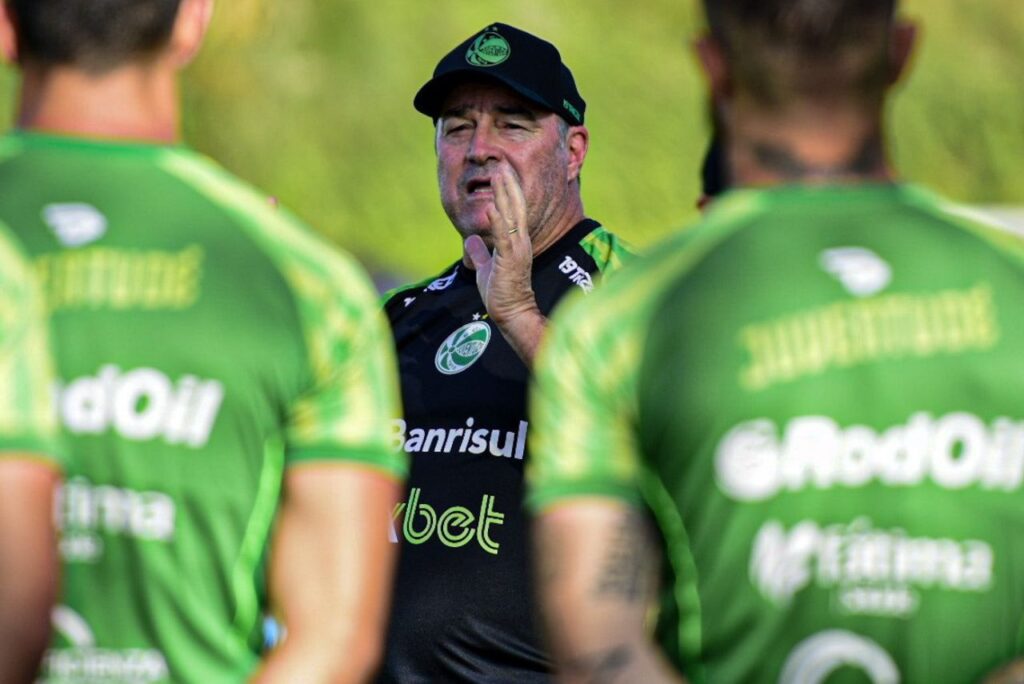 Treinador Pintado aparece de frente, entre jogadores de costas, em treino do Juventude em 2023